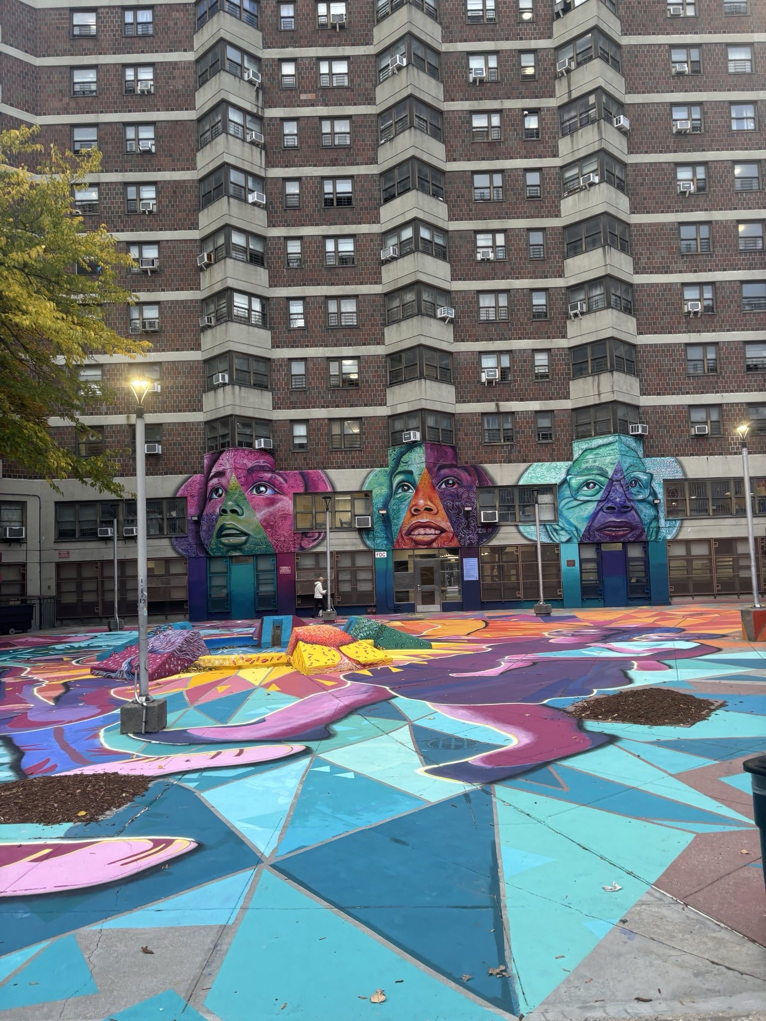 Village of Generations mural at Amsterdam Houses featuring colorful faces and community art